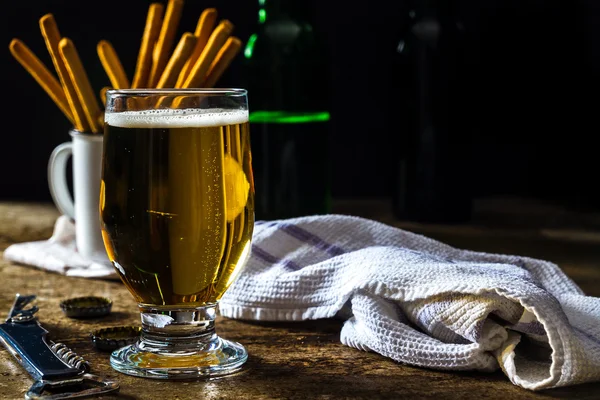 Vaso de cerveza ligera sobre una mesa de color marrón oscuro con snacks — Foto de Stock