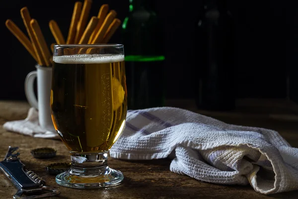 Glas light bier op een donkere bruin tafel met snacks — Stockfoto