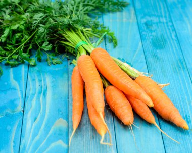 Renkli turkuaz mavi boyalı woode üzerinde taze havuç demet