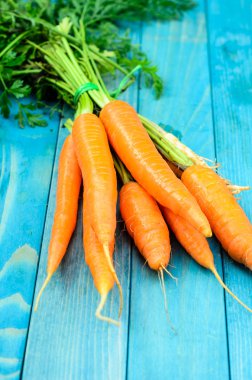 Renkli turkuaz mavi boyalı woode üzerinde taze havuç demet