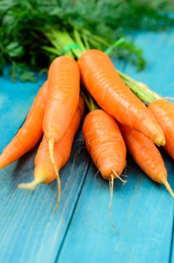 Renkli turkuaz mavi boyalı woode üzerinde taze havuç demet