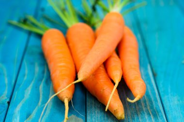 Renkli turkuaz mavi boyalı woode üzerinde taze havuç demet