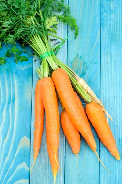 Renkli turkuaz mavi boyalı woode üzerinde taze havuç demet