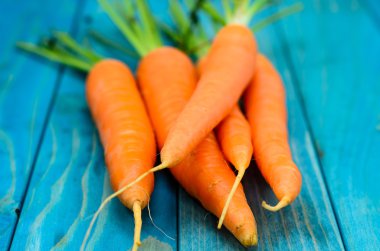 Renkli turkuaz mavi boyalı woode üzerinde taze havuç demet