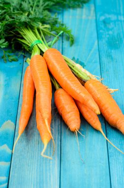 Renkli turkuaz mavi boyalı woode üzerinde taze havuç demet