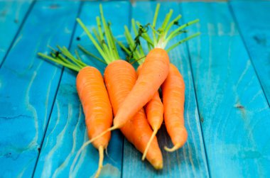 Renkli turkuaz mavi boyalı woode üzerinde taze havuç demet