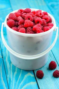 Raspberry bucket on white woodne boards