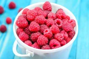 Raspberry bucket on white woodne boards