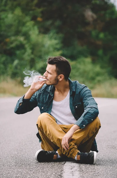 Hipster sitter på vägen — Stockfoto