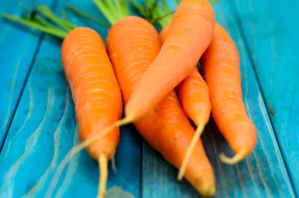 Renkli turkuaz mavi boyalı woode üzerinde taze havuç demet