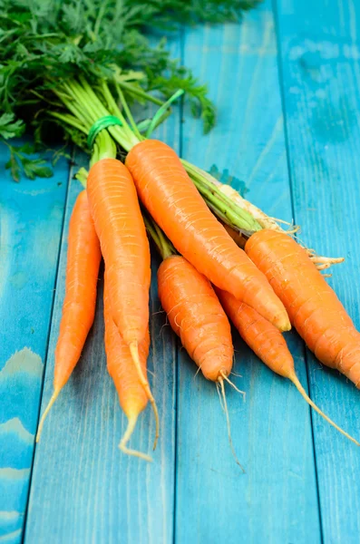 Renkli turkuaz mavi boyalı woode üzerinde taze havuç demet