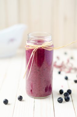 Cranberry and black currant smoothie in glass jars on a white wo