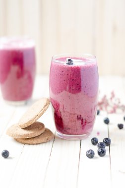 Cranberry and black currant smoothie in glass with cookies on a 