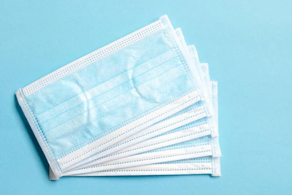 Medical masks on a blue background, top view. Surgical medical mask isolated on blue background. Prevent coronavirus. Medical 3-ply surgical mask to cover the nose and mouth. Disposable medical mask. — Stock Photo, Image