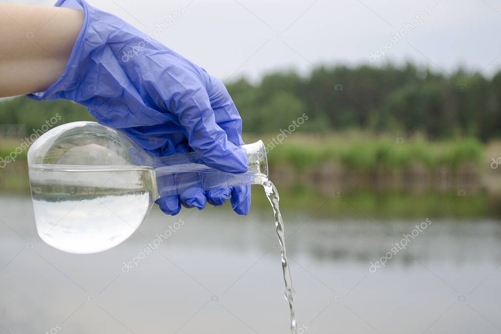 Sample of water from a lake, river. Water sampling by a laboratory assistant for quality indicators. Water sampling from a river.