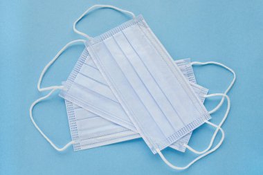 Mavi arka planda tıbbi maskeler, üst manzara. Mavi arka planda cerrahi tıbbi maske var. Koronavirüsü önle. Ağzı ve burnu örtmek için tıbbi 3 katlı cerrahi maske. Tek kullanımlık tıbbi maske