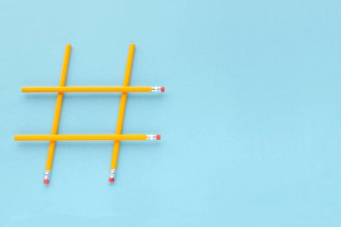 Fotokopi alanı, üst görünümü olan mavi arkaplandaki sarı kalemlerden yapılmış etiket işareti. Fotokopi alanı olan mavi arka planda tahta sarı kalemler. Etiket internette popülerdir. Minimalizm