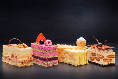 Farklı dolguları olan kek parçaları, koyu arkaplanda lezzetli tatlılar.