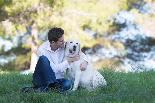 彼の年長のラブラドール犬にキスの若い男性 — ストック写真