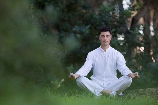 young man sitting in the park doing meditation