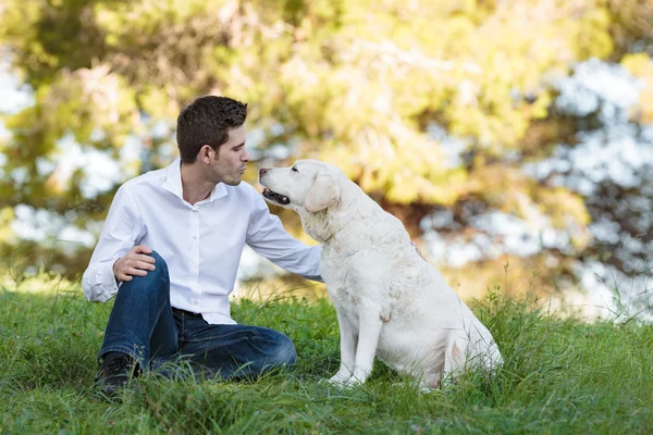 若い男が公園で彼の非常に古い犬にキス — ストック写真