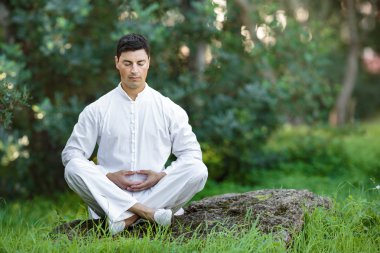 taş üzerinde açık havada oturup meditasyon yapan erkek