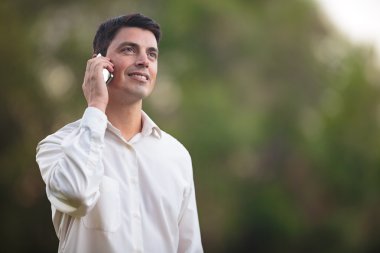 Genç adam dışarıda telefonla konuşuyor.