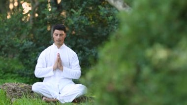 genç latin erkekler beyaz giyim parkta meditasyon yapıyor