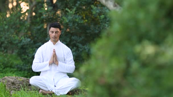 Genç latin erkekler beyaz giyim parkta meditasyon yapıyor — Stok video