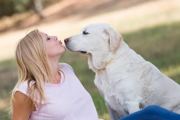 Nastolatka dziewczyny całuje jej bardzo stary starszy pies labrador w parku — Zdjęcie stockowe