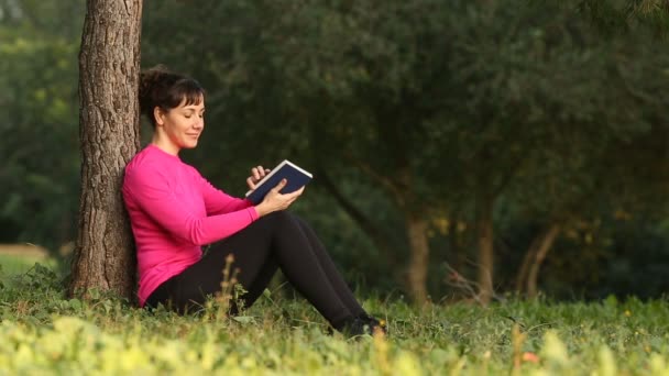 Frau liest Buch in der Natur — Stockvideo