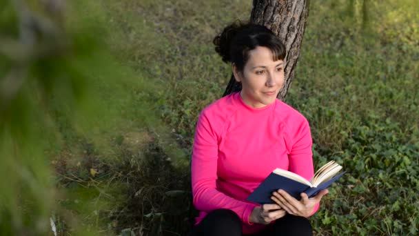 Νεαρή γυναίκα διαβάζει βιβλίο στο πάρκο — Αρχείο Βίντεο