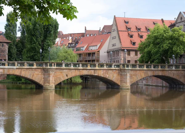 ドイツの伝統的な中世の半木造旧市街建築と橋がドイツのニュルンベルクのペグニッツ川に架かっている — ストック写真