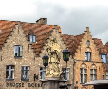 Bruges, Belçika - 8 Mayıs 2019: Gotik tarzı binalar ve köprülerin koruyucu azizi Sint Johannes Van Nepomuk, ve Batı Flanders 'ın tarihi merkezinde dini bir heykel