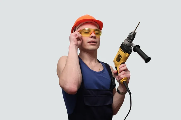 Egy drill és egy sisak egy fiatal, szexi férfi portréja — Stock Fotó