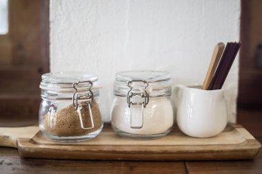 jars with different kinds of sugar and wooden sticks  on wooden table