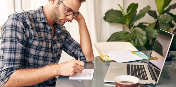 Psaní poznámek dolů infront z notebooku doma — Stock fotografie