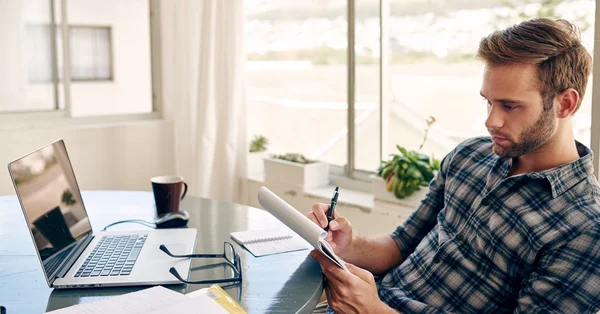Genç işadamı ev ofisinde notlar