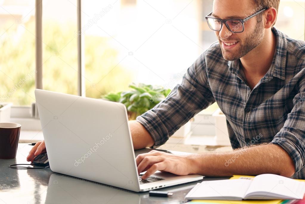 Happy man sitting and working at his desk from home