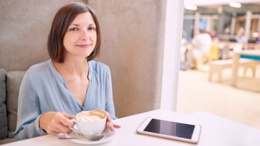 Olgun kadın fotoğraf makinesi kahve ve bir tablet ile gülümseyen