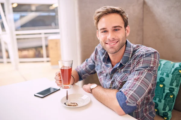 Homem bonito olha em linha reta para a câmera sentada no café — Fotografia de Stock