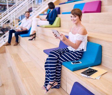 Bir tablet tutan kameraya gülümseyen güzel kız öğrenci