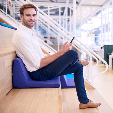 Yakışıklı beyaz erkek akıllı telefonu tutarken kameraya gülümsüyor