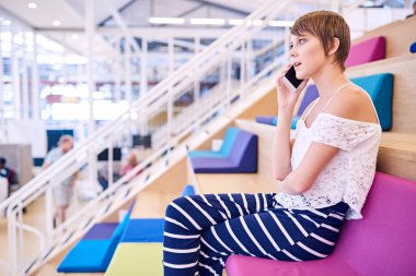 Cep telefonunda kısa kahverengi saçlı genç kadın