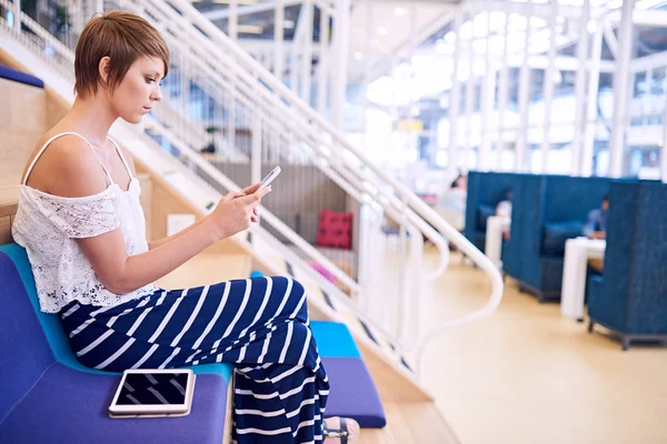 Onun smartphone üzerinde oturma sırasında mesajlaşma yaratıcı kadın tasarımcı