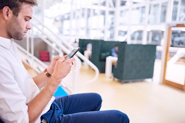 Vuxen man upptagen textning på sin moderna lätta smartphone — Stockfoto