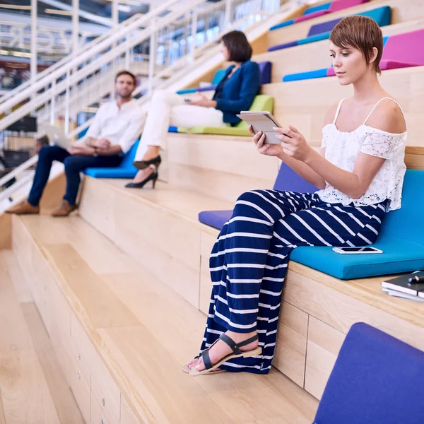 Mujer creativa joven ocupada usando una tableta sentada en los escalones Fotos De Stock