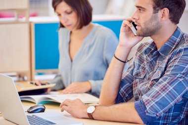 Arka planda çalışan kadın ile telefonda konuşan adam