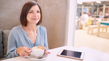 Olgun kadın fotoğraf makinesi kahve ve bir tablet ile gülümseyen