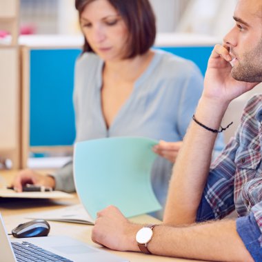 Arka planda çalışan kadın ile telefonda konuşan adam